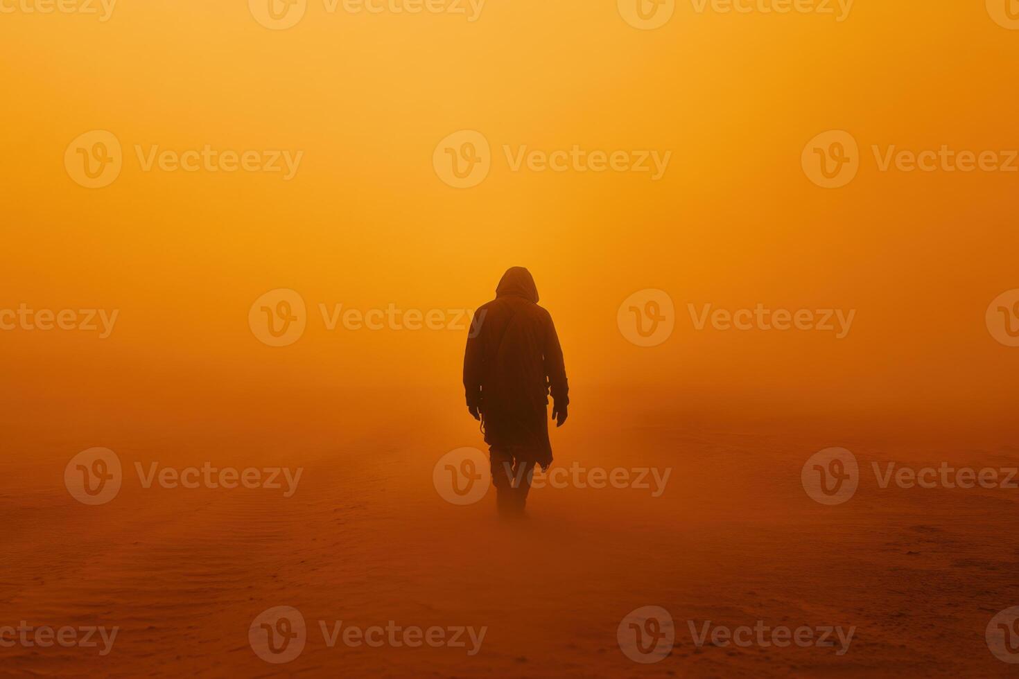 Person walks away through orange dust. Silhouette of figure in cloak on desert landscape. Mysterious hazy atmosphere. Walking into the unknown. Desert travel. photo
