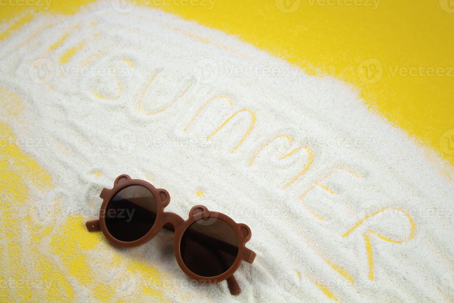 On a yellow sand background the inscription Summer and sunglasses. The concept of tourism, vacation photo