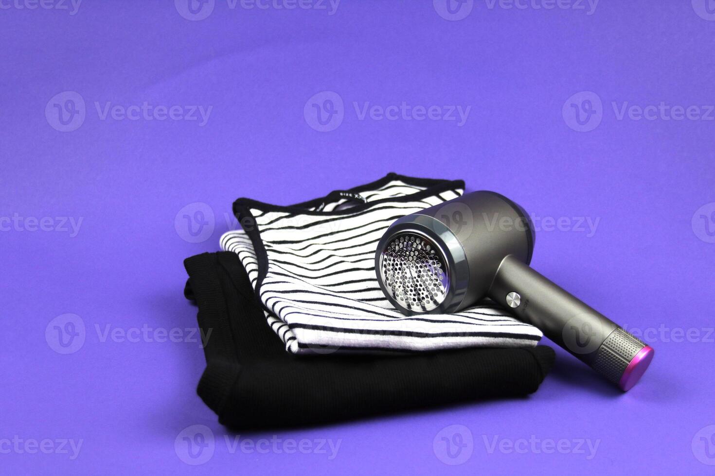 On a purple background are folded basic T-shirts. The lint machine means clean clothes without unnecessary waste. photo