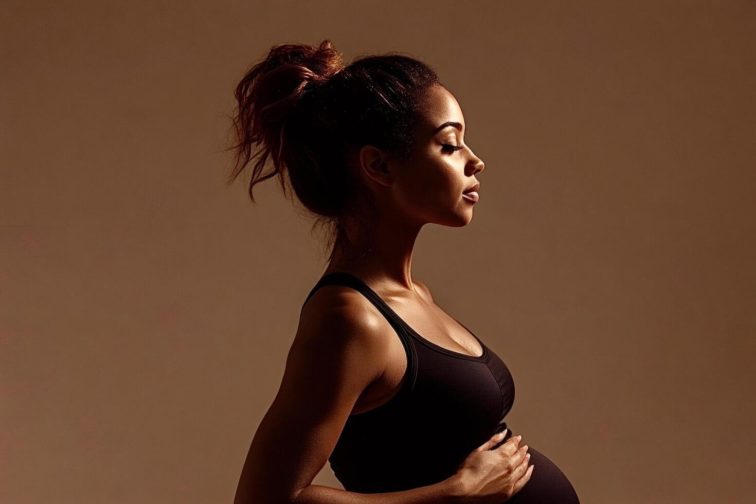Pregnant model posing in profile, embracing her belly photo