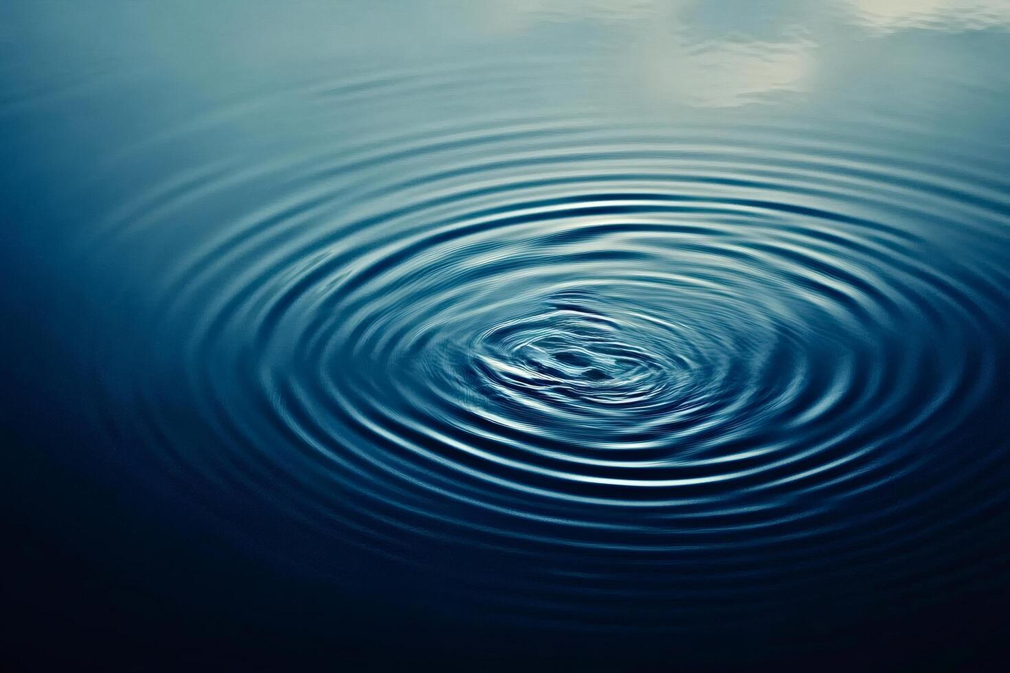 Water droplet creating concentric ripples on calm surface photo