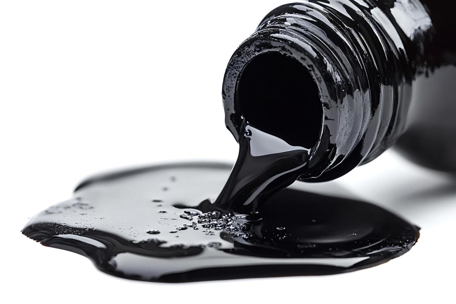 Black viscous liquid pouring from a bottle onto white background photo
