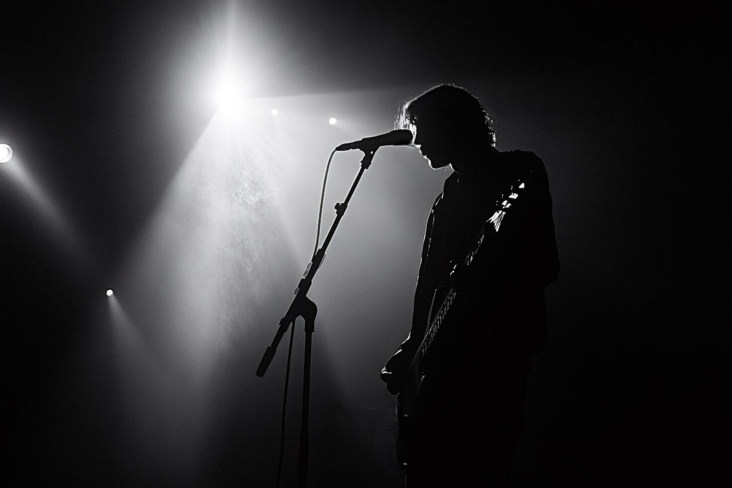 Guitarist singing and playing guitar on stage under spotlights photo