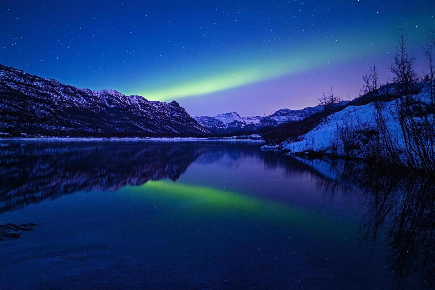 Aurora borealis reflecting in a lake surrounded by snowy mountains photo