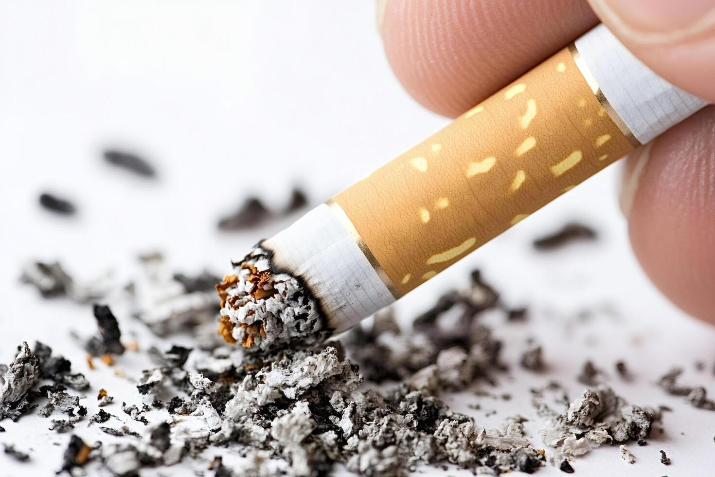 Fingers holding cigarette butt leaving ashes on white background photo