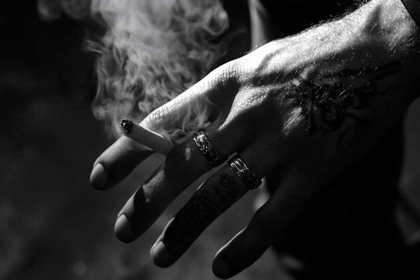 Tattooed hand holding a lit cigarette with smoke photo