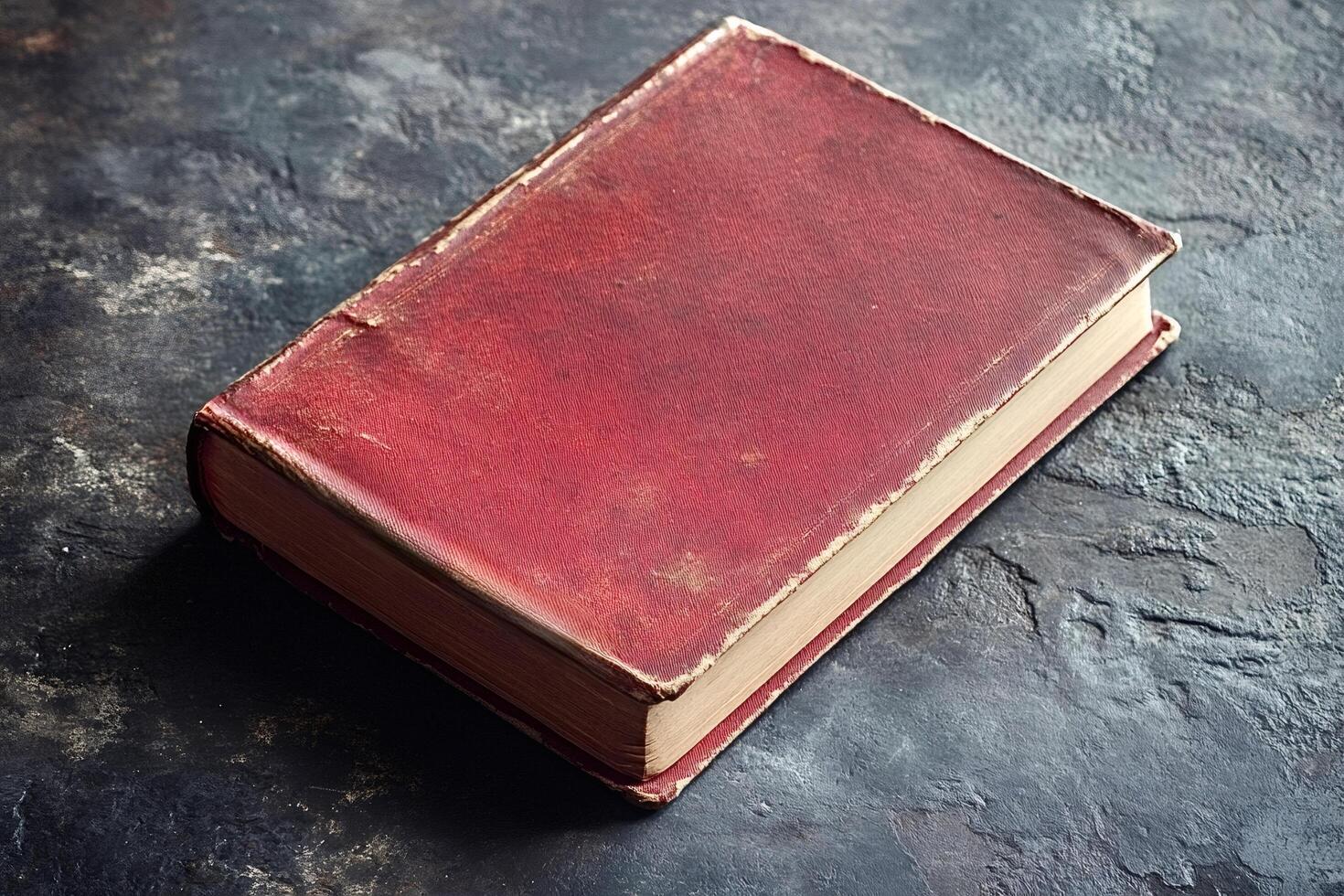 Old red book resting on a dark stone surface photo