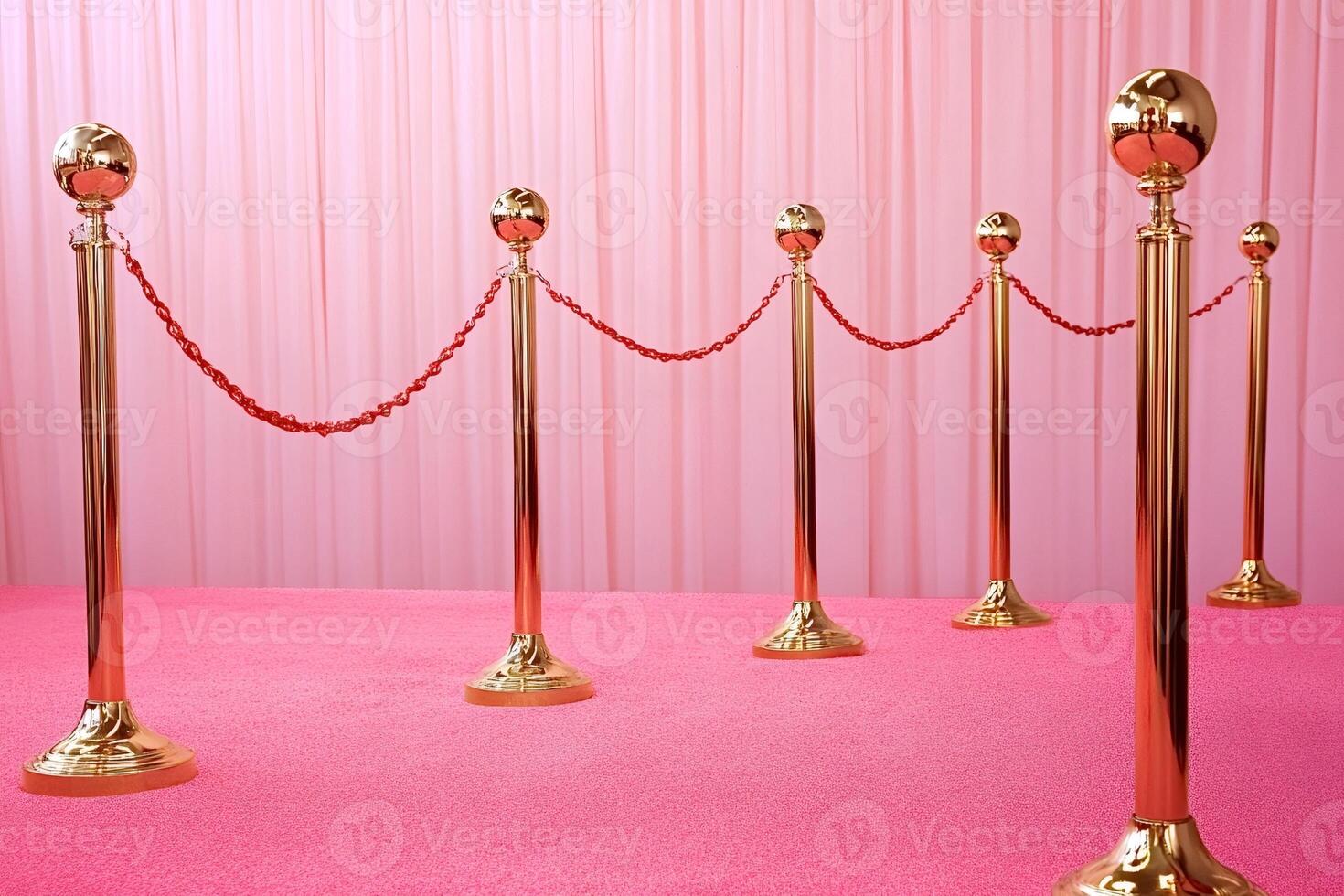 Golden stanchions with red ropes bordering pink carpet leading to a pink curtain photo