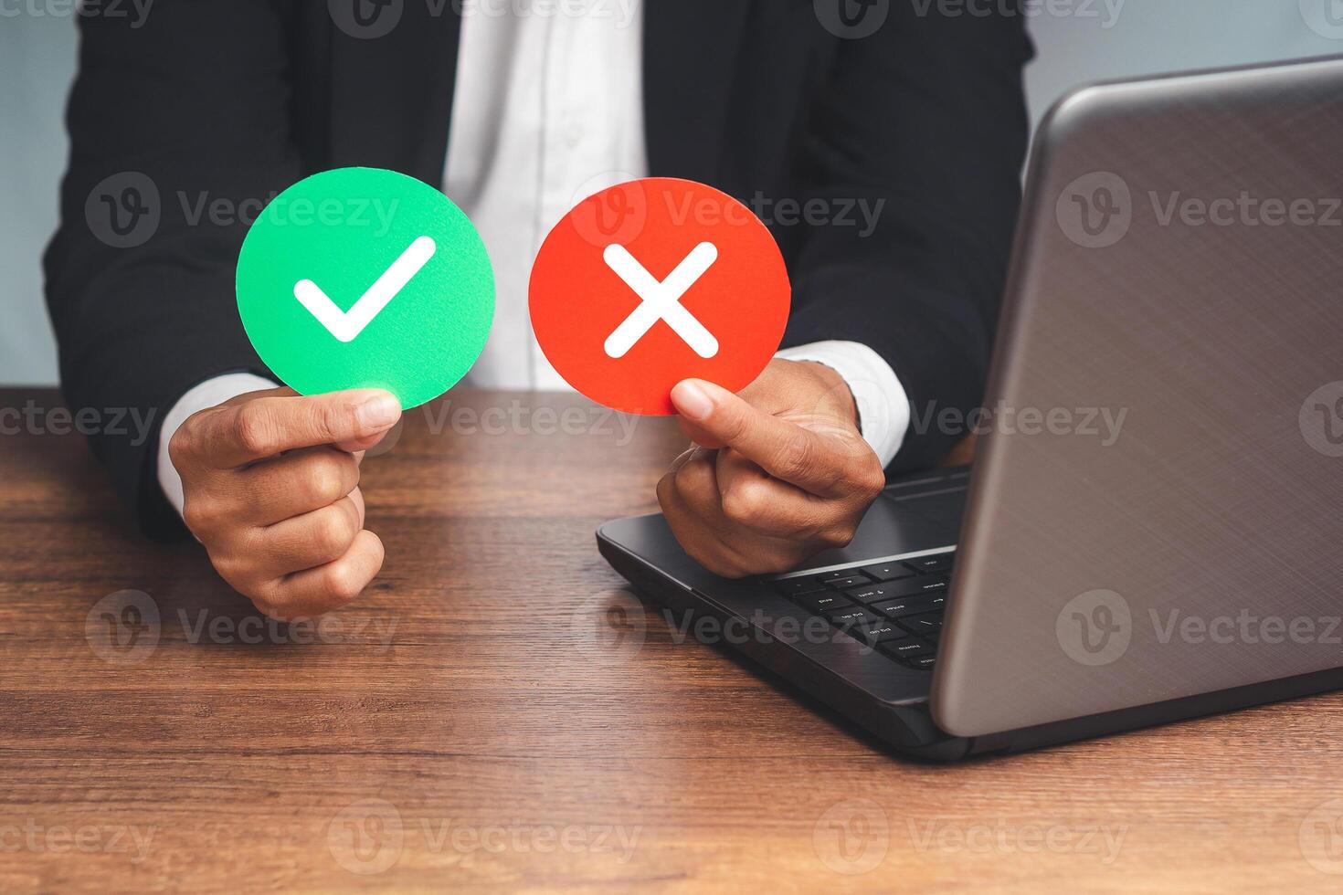 Hand holding two green and red paper with a checkmark and cross photo