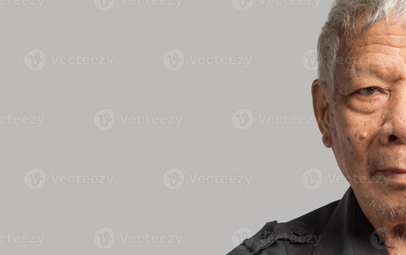Close-up of senior man half face standing on a gray background photo