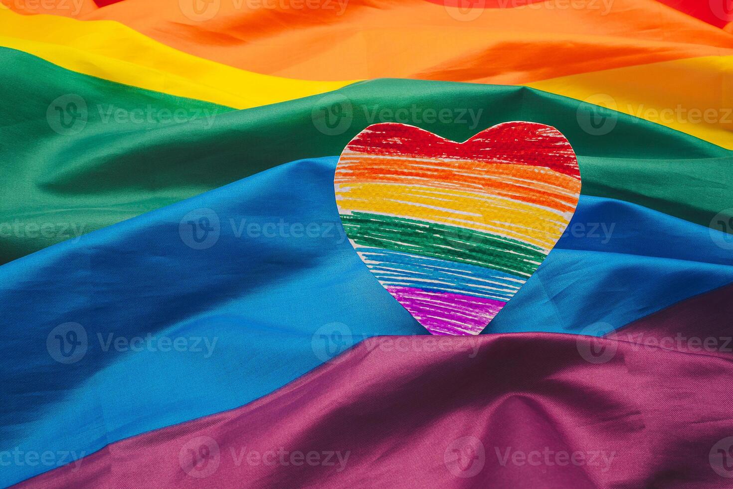 A rainbow heart shape symbol made from paper over the rainbow flag or LGBT flag background. photo