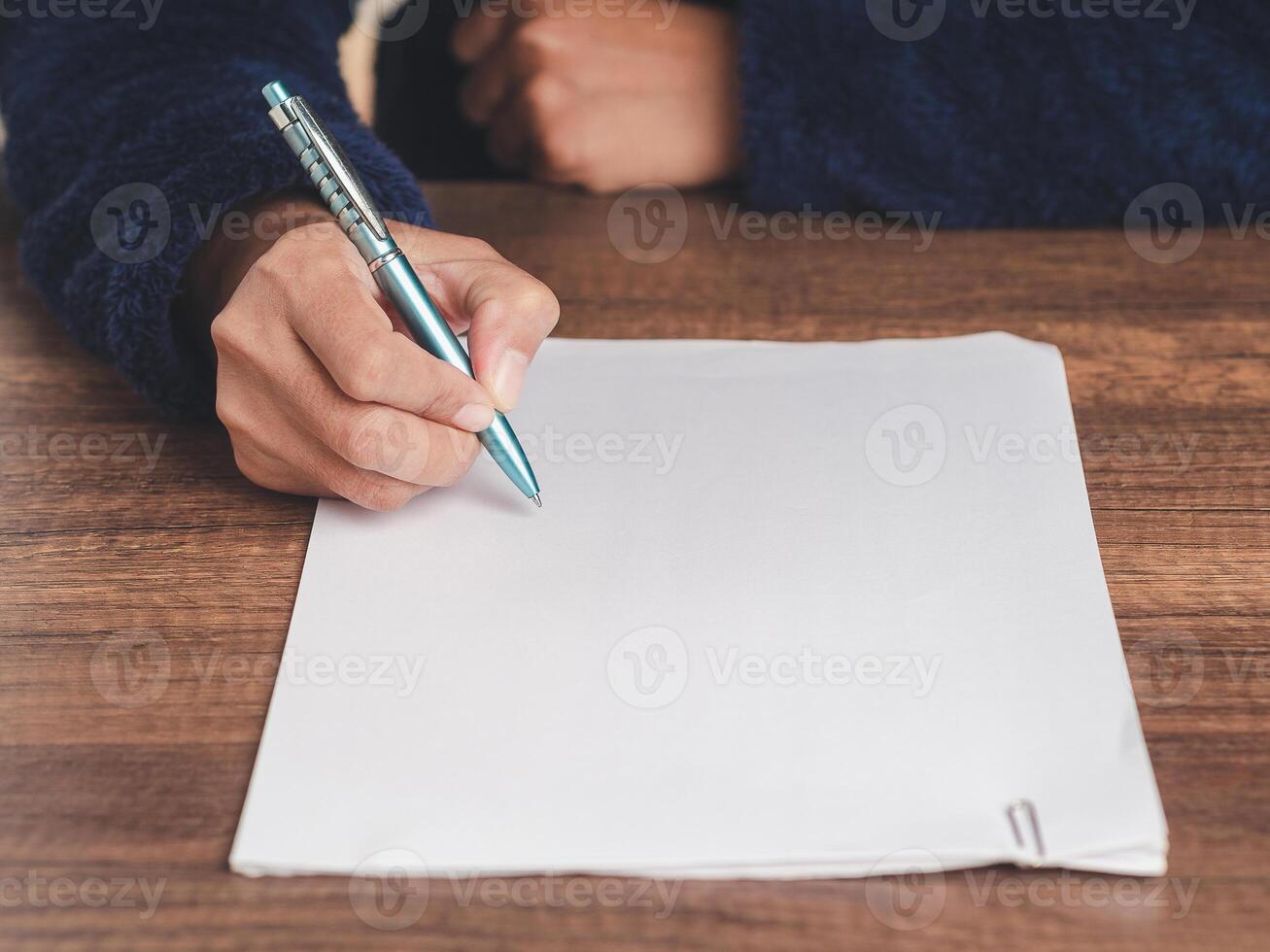 Close-up of businessman in a sweater signing a lease contract or agreement while sitting at the table. photo