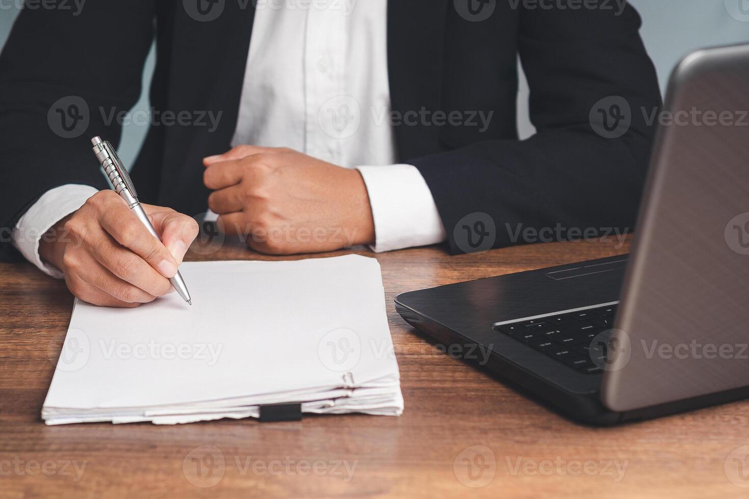 Close-up of a businessman in a suit signing a lease contract or agreement while sitting at the table. photo