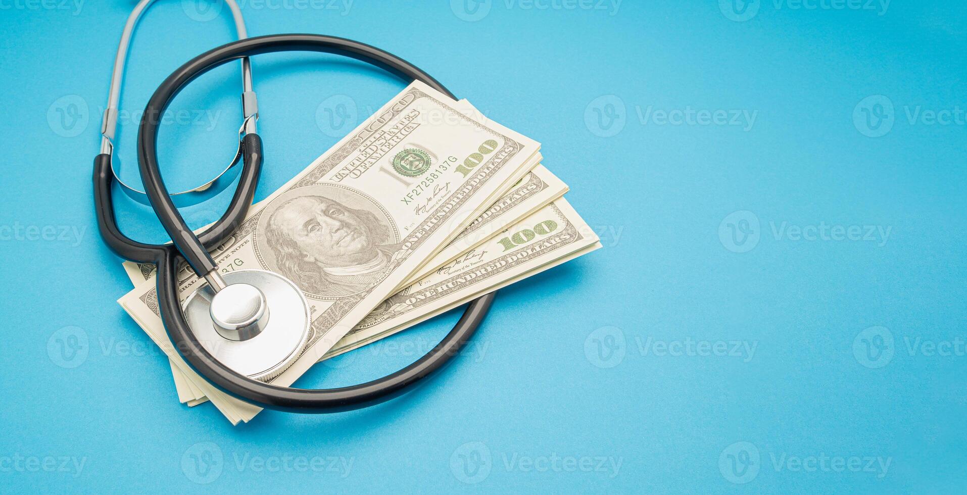 Top view of a stethoscope and US dollar banknotes on a blue background. photo