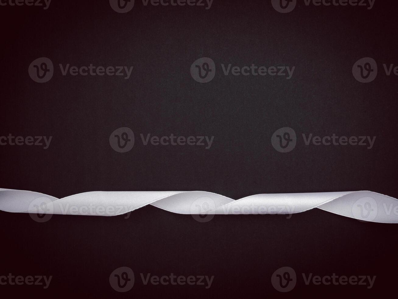 Top view of a white ribbon and wooden cubes with the letters RIP on a black background. photo