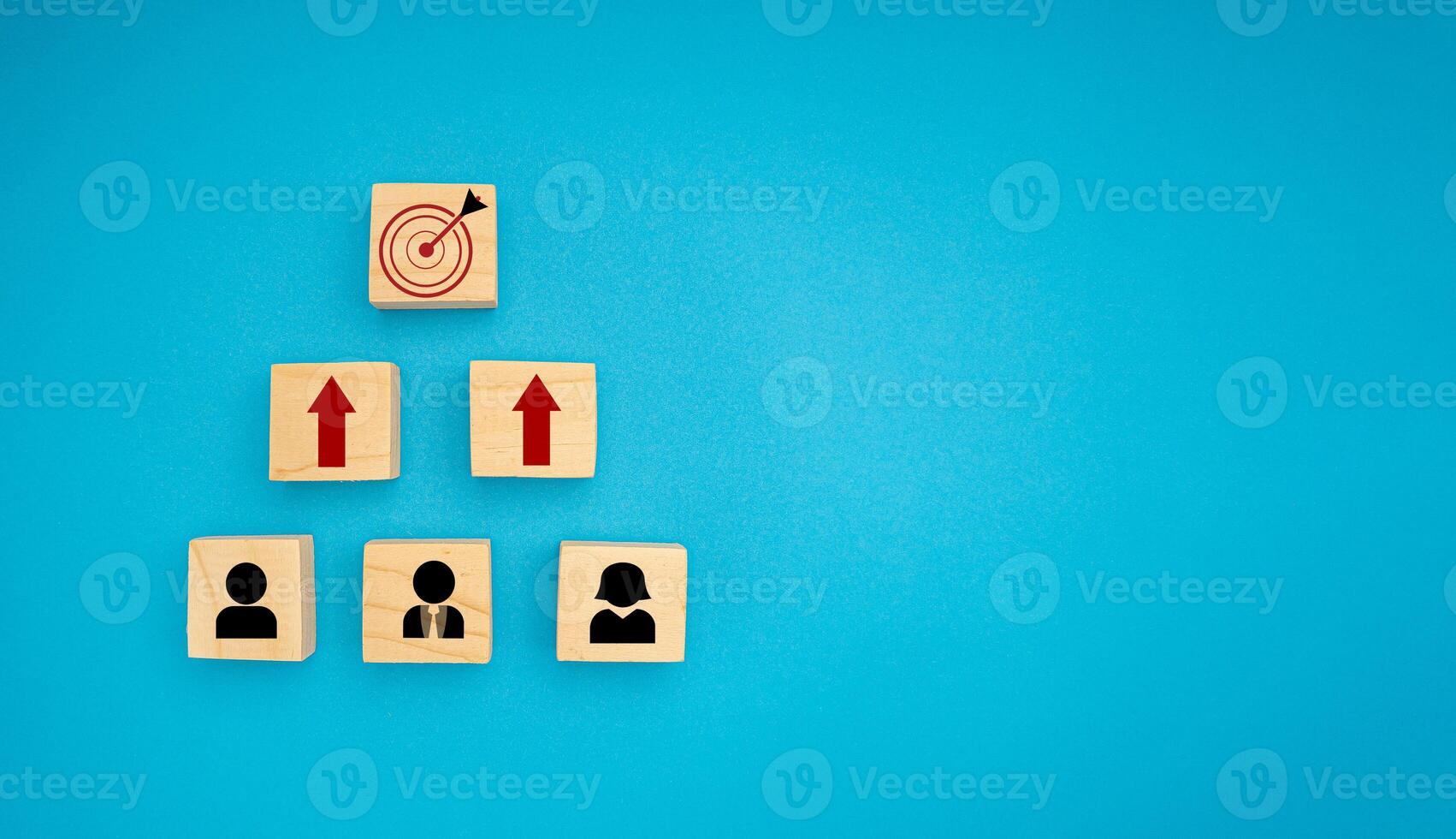 Wooden blocks with black people and red arrow icons pointing to the dartboard icon on a blue background photo