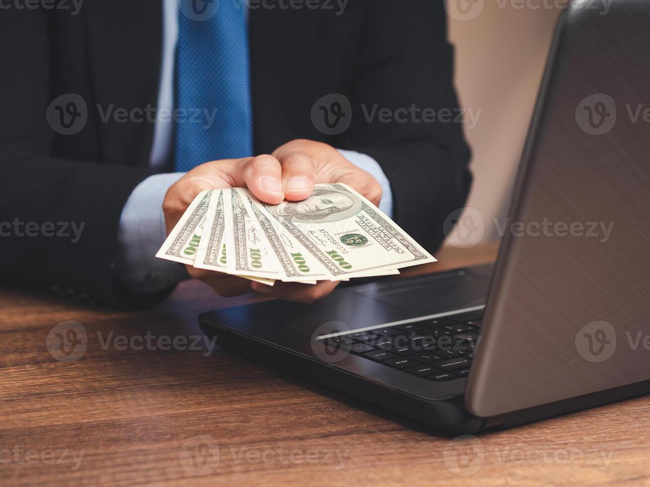 Businessman in a suit holding US dollar bills while sitting in the office photo