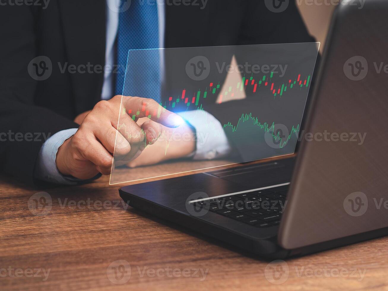 Hand of a businessman pointing at graph stock on a virtual screen while sitting at the table in the office photo