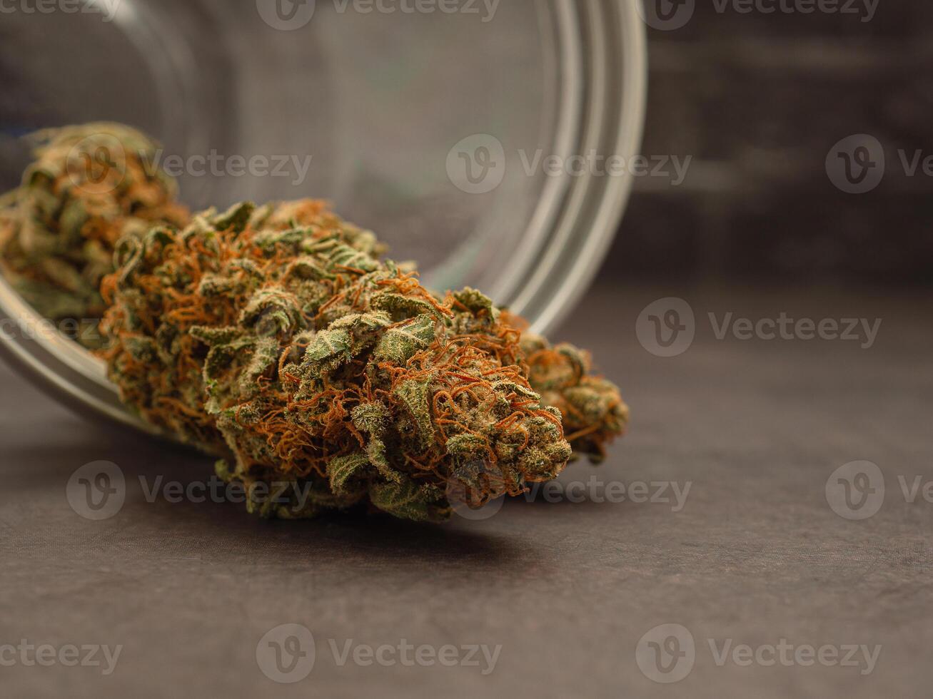 Close-up of dry cannabis buds out of a glass jar on a gray background photo