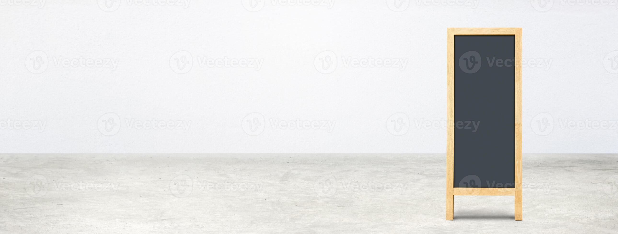 Blank blackboard on a concrete floor with a white wall. photo