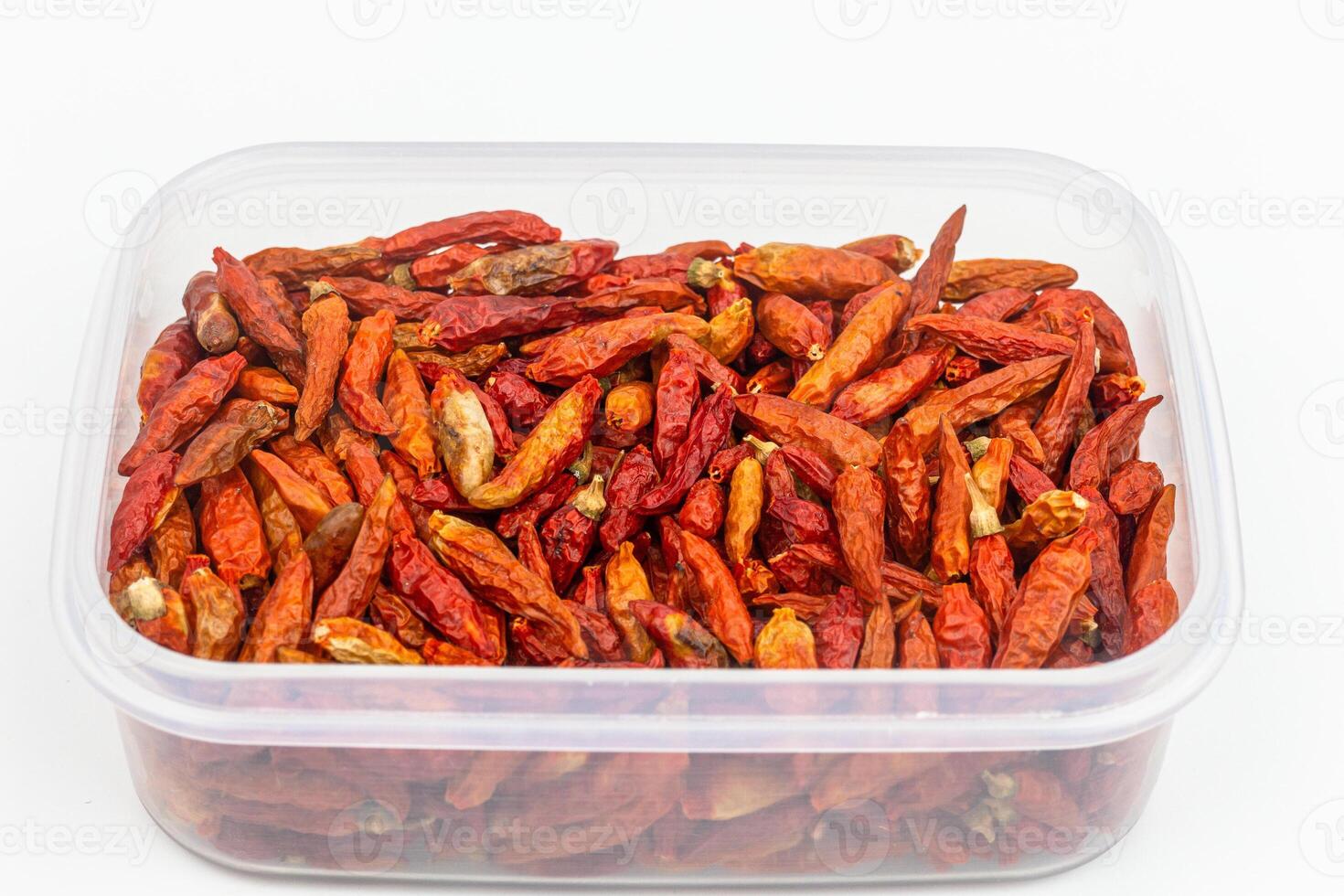 Dried red chilli pepper in plastic box on white background. photo