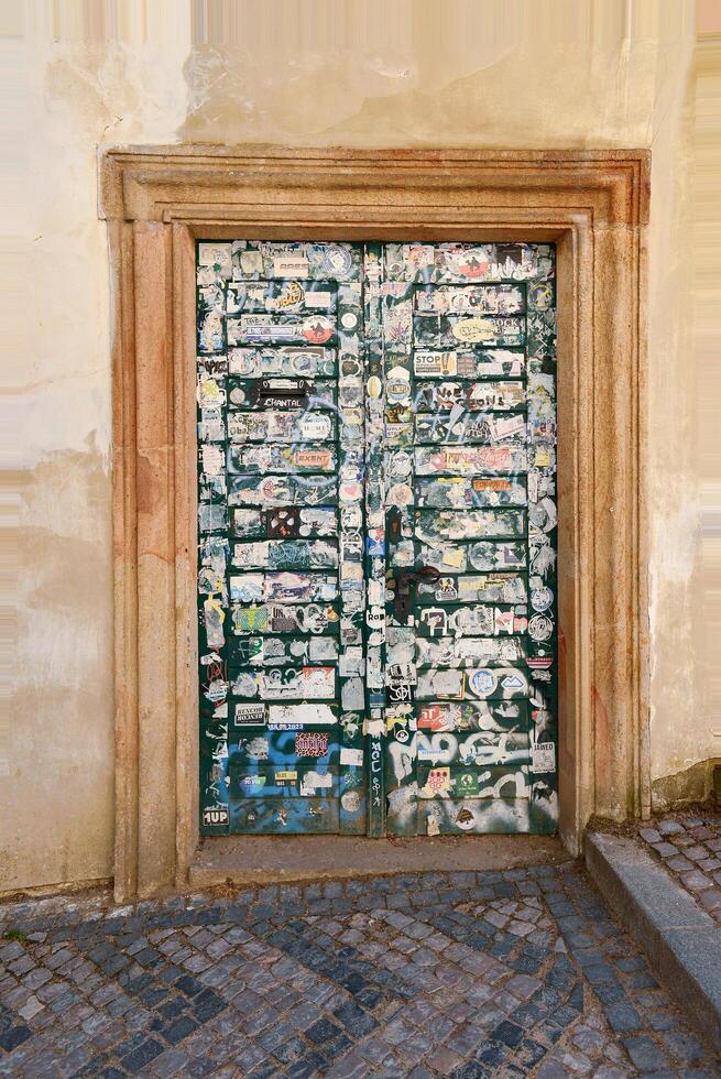 Prague, Czechia. March 27, 2025. Old iron door covered with torn pieces of paper. photo