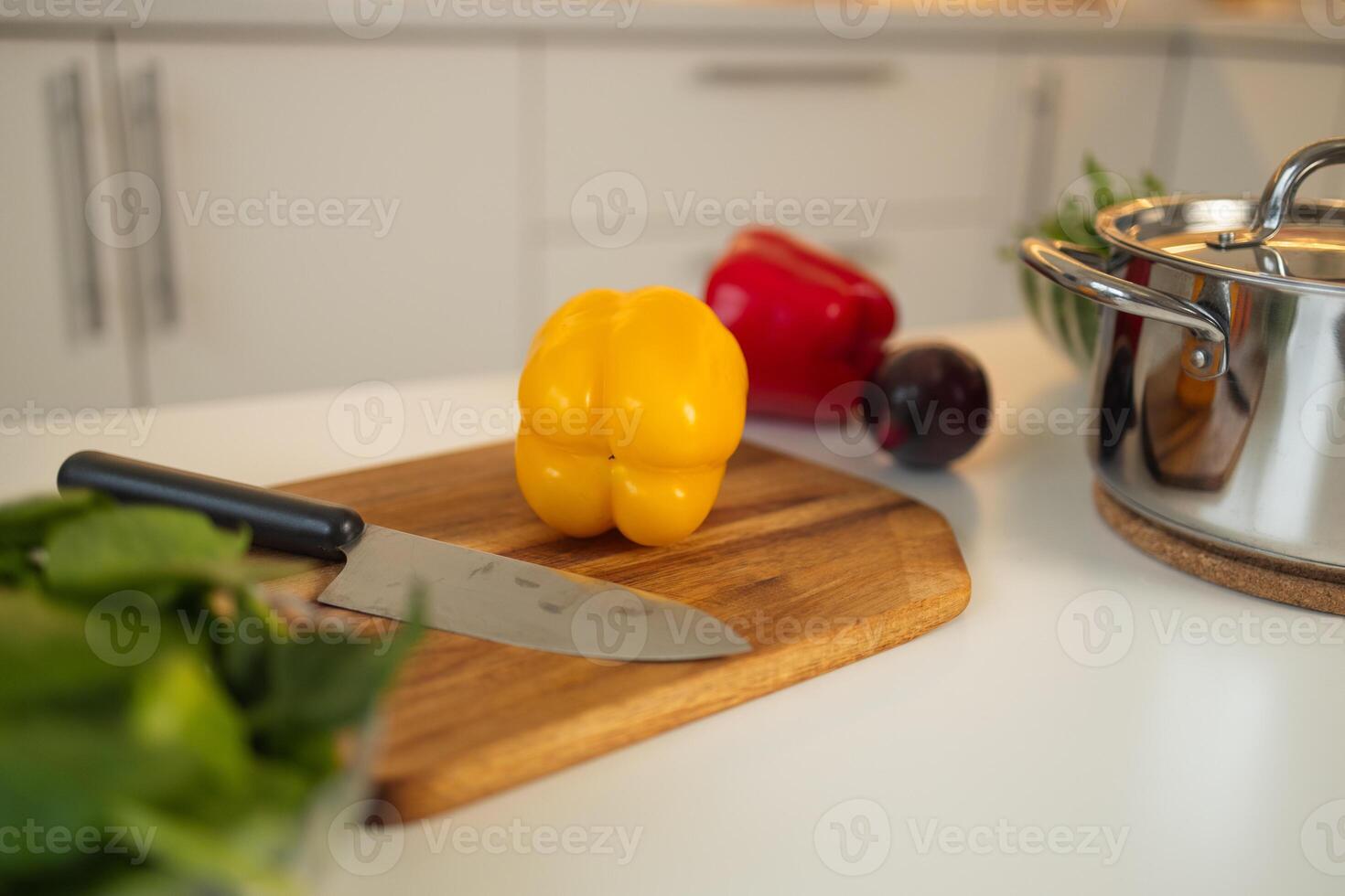 Yellow bell pepper on a wooden cutting board in the kitchen with knife. photo