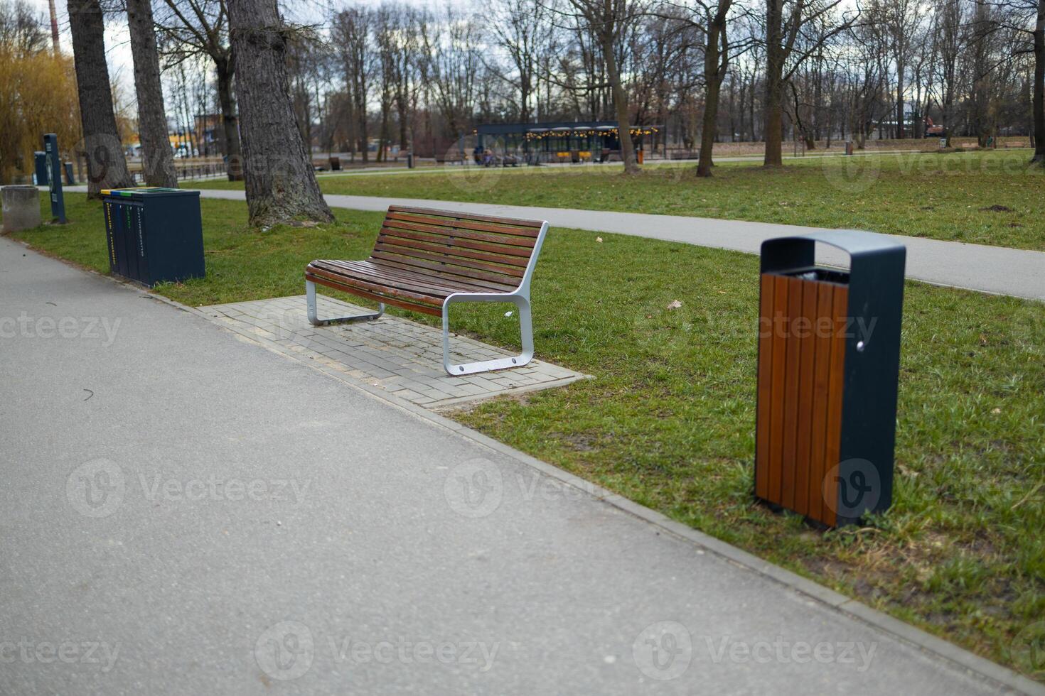 Park Bench with Trash Bins along a Path in a Public Park photo