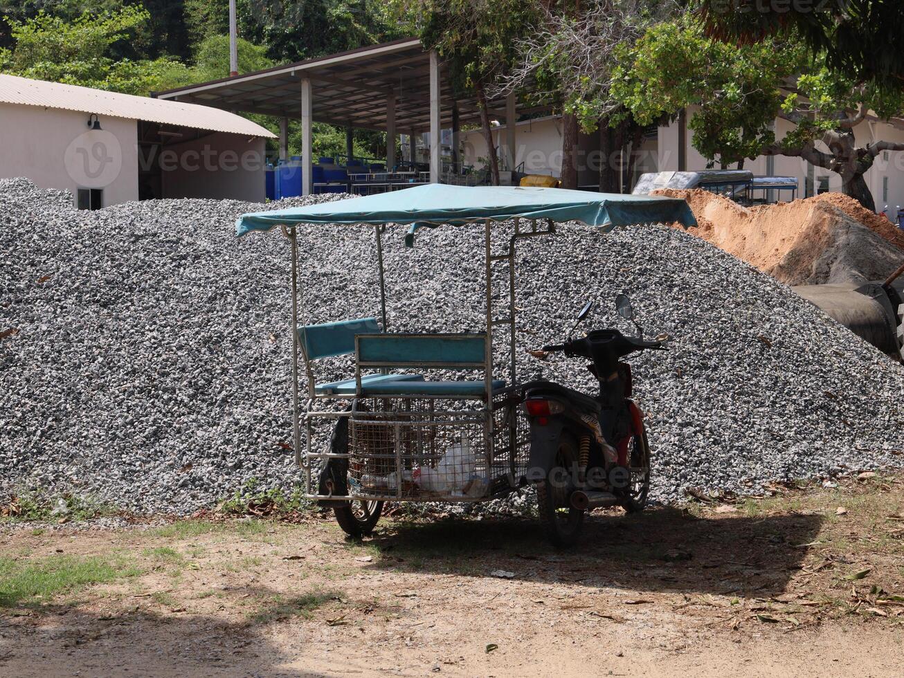 A Vintage Trike is parked under a Shelter by a large Gravel Pile, showing the industrial vibe photo