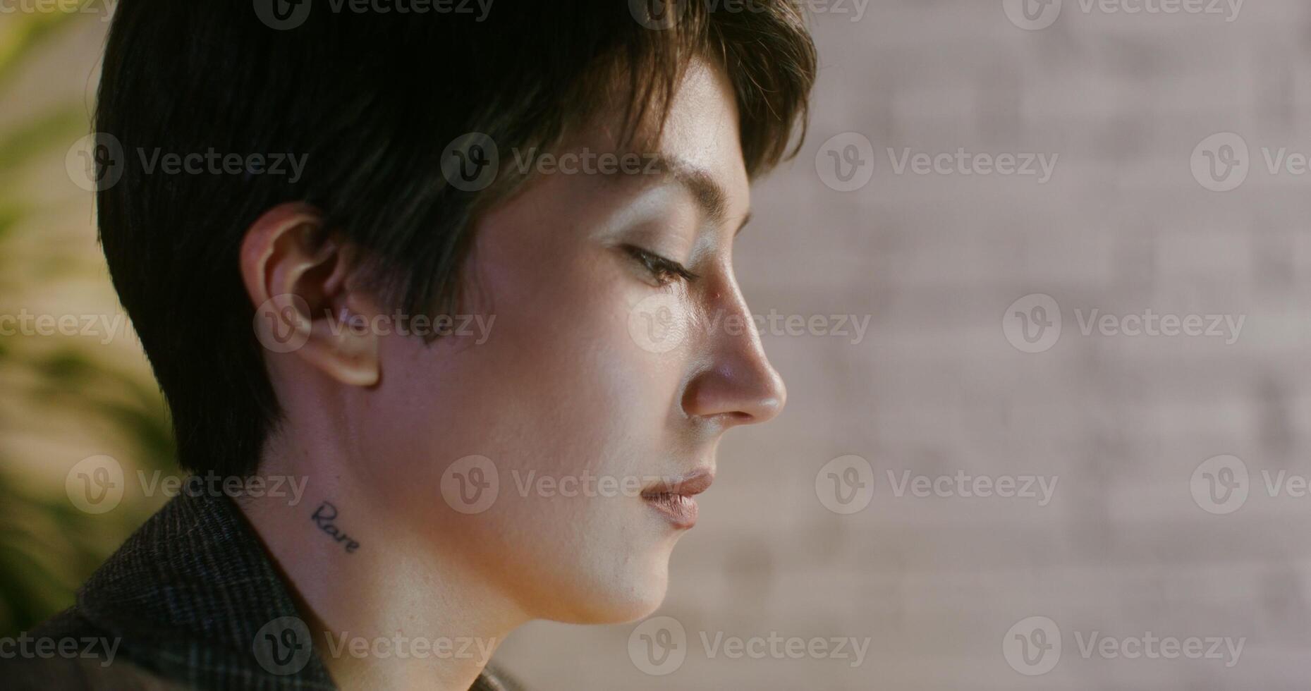 A woman with a tattoo on her neck looking away photo