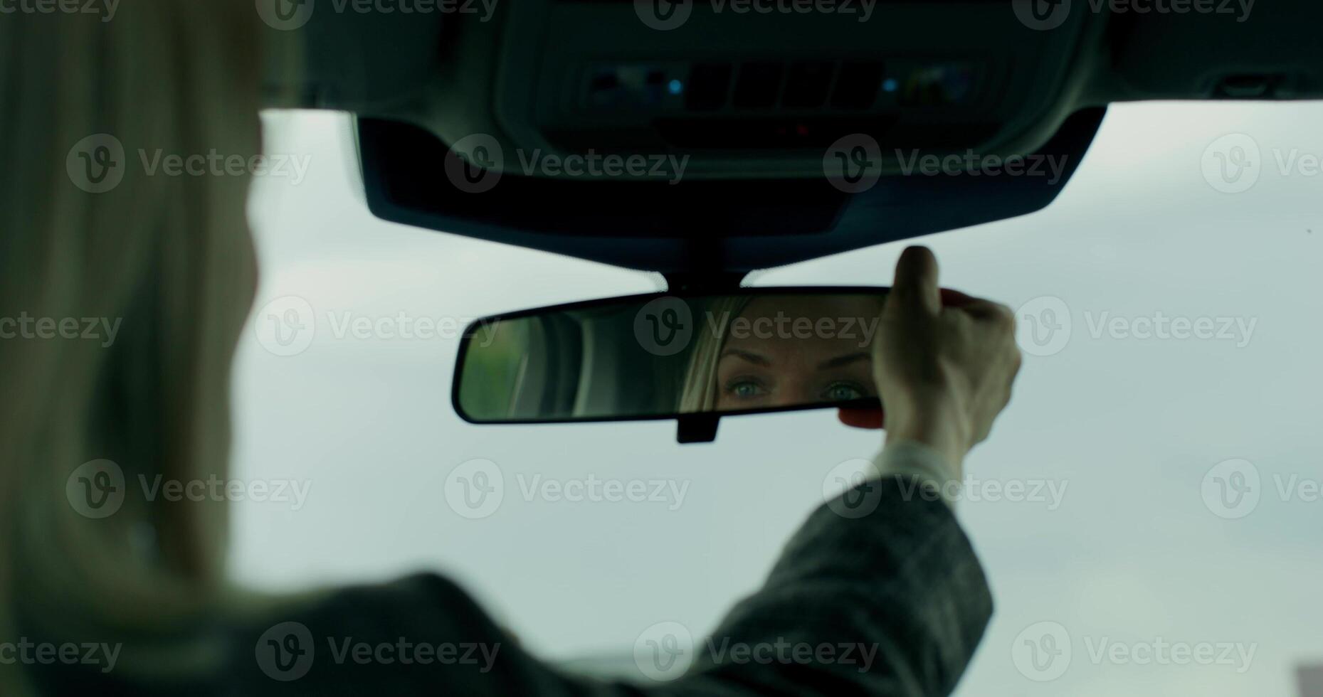 A woman holding a mirror in the rear view mirror of a car photo