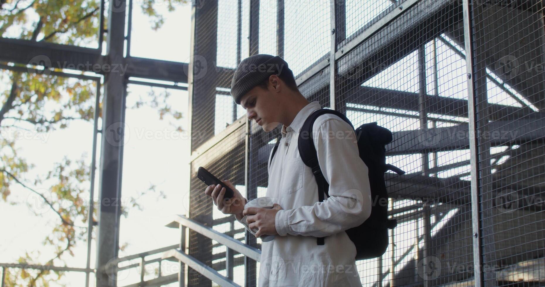 A man with a backpack and hat standing on a stairway photo