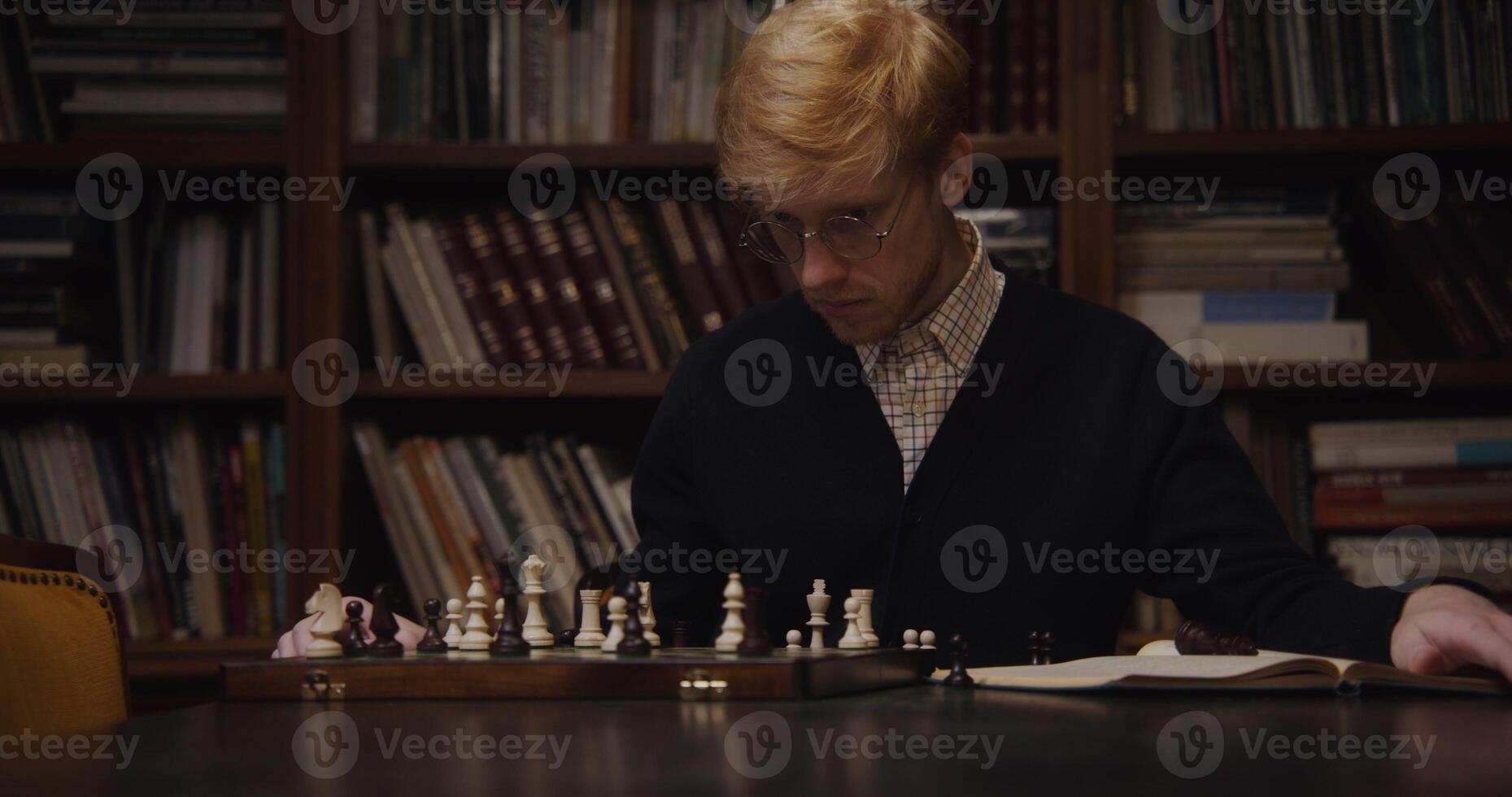 A man in glasses playing chess on a table photo