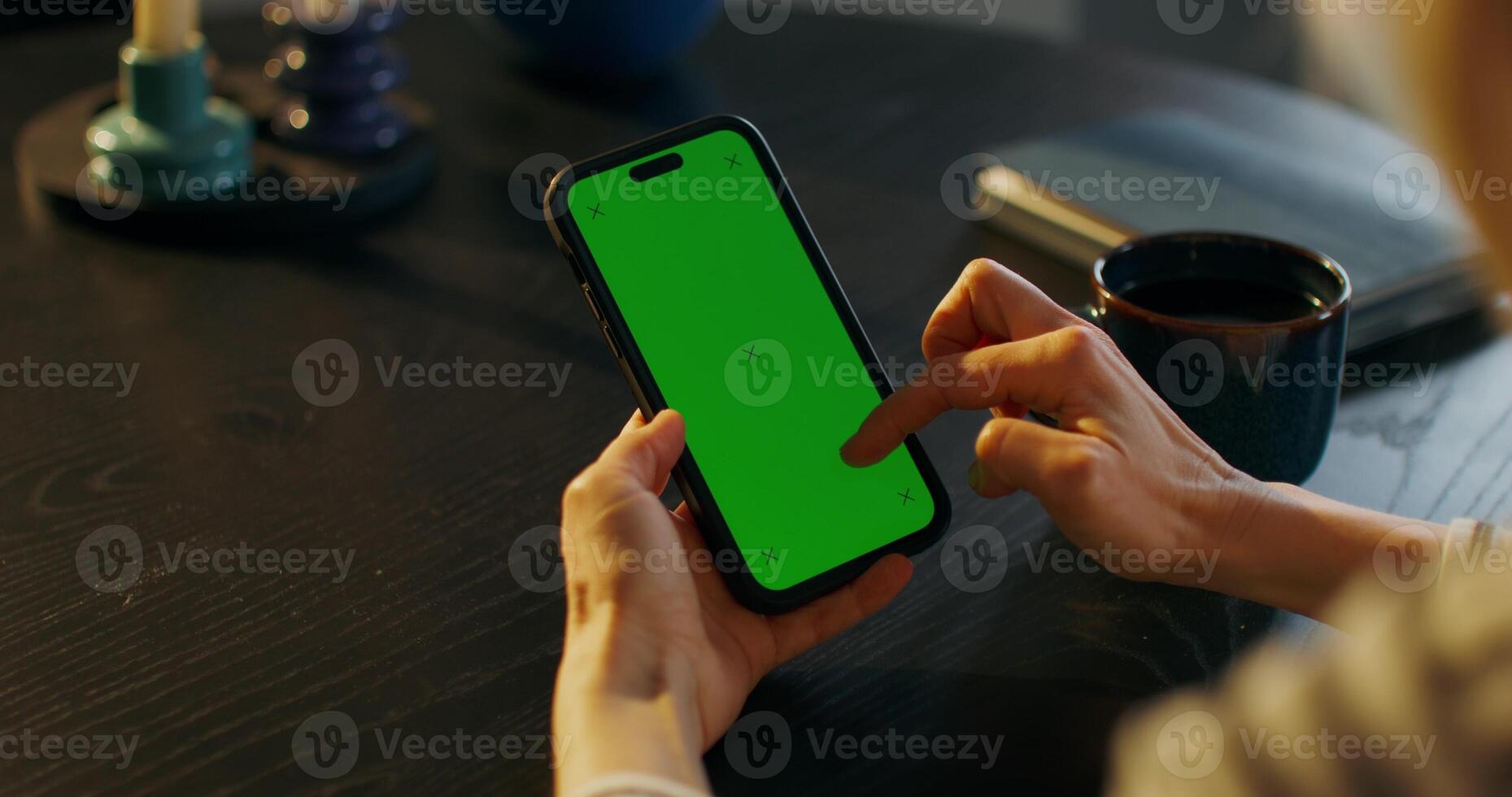 Woman using smartphone with green screen at table photo