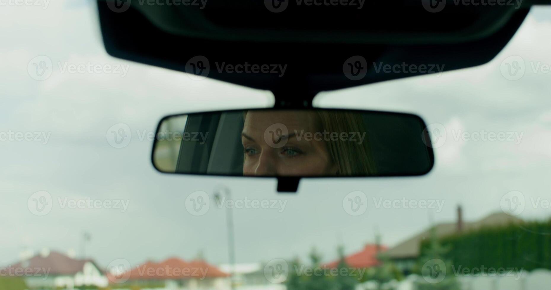 A woman is looking out the side mirror of a car photo