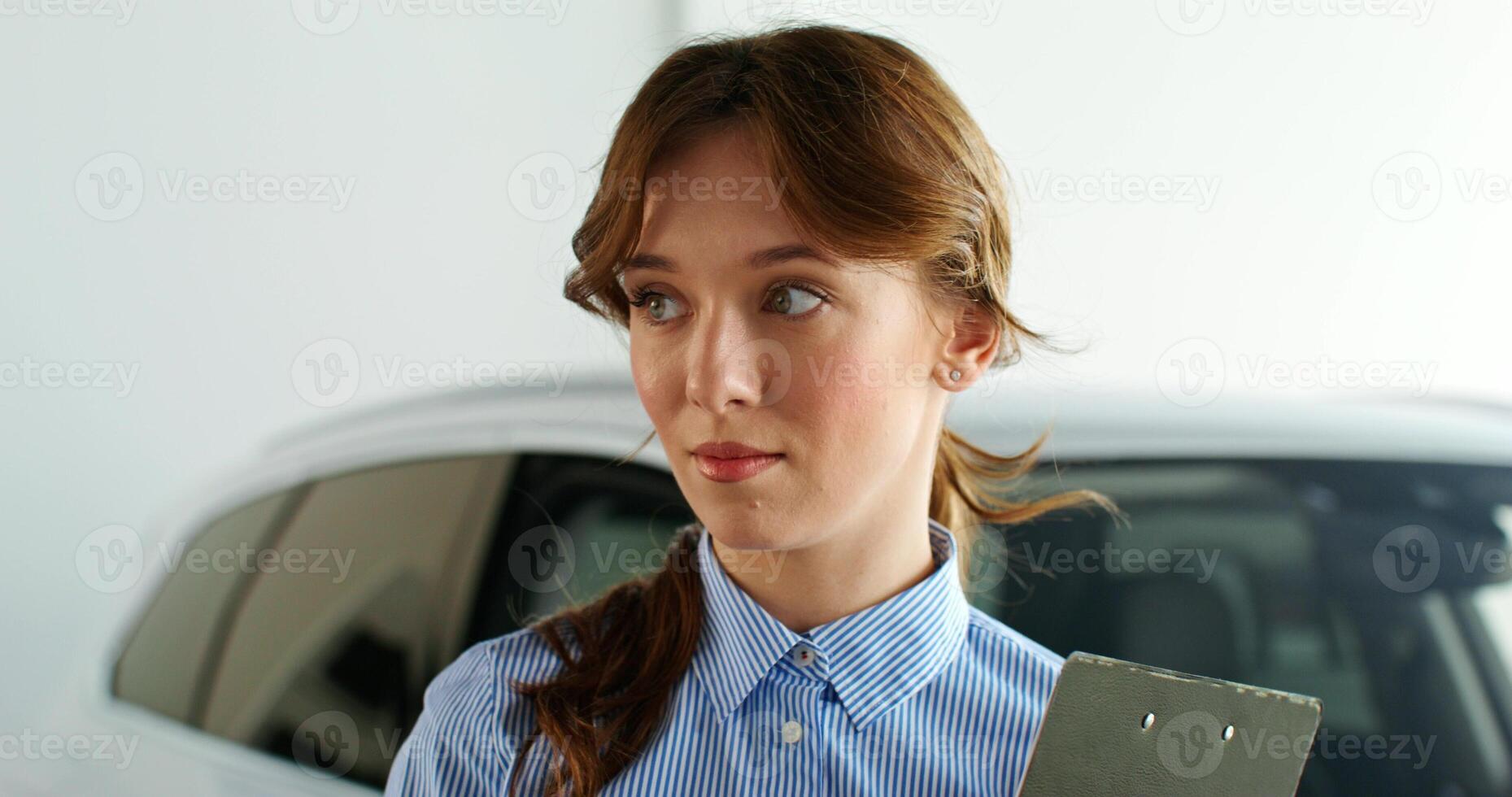 A woman holding a clipboard in front of a car photo