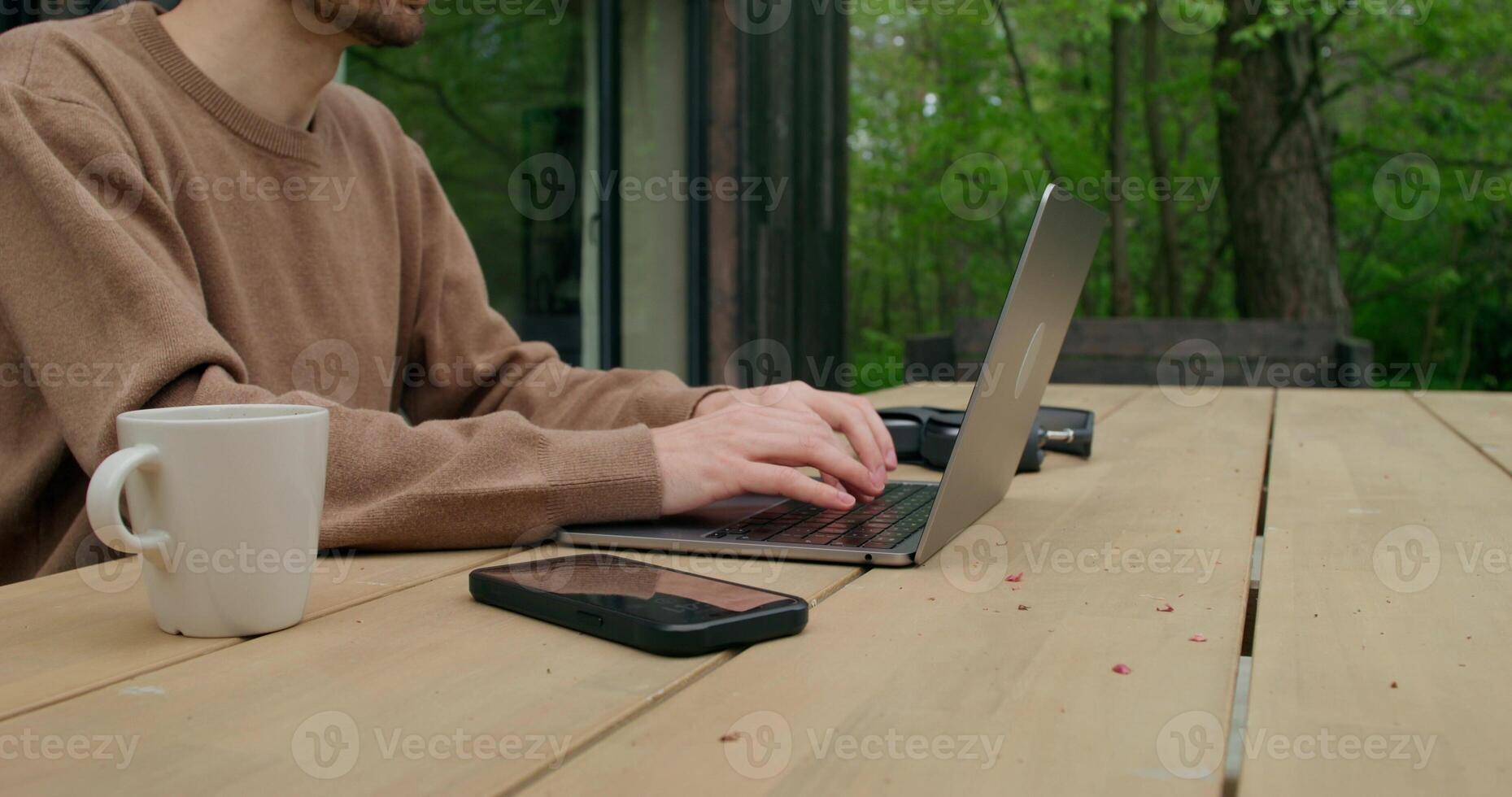 A man sitting at a table with a laptop and a cup photo