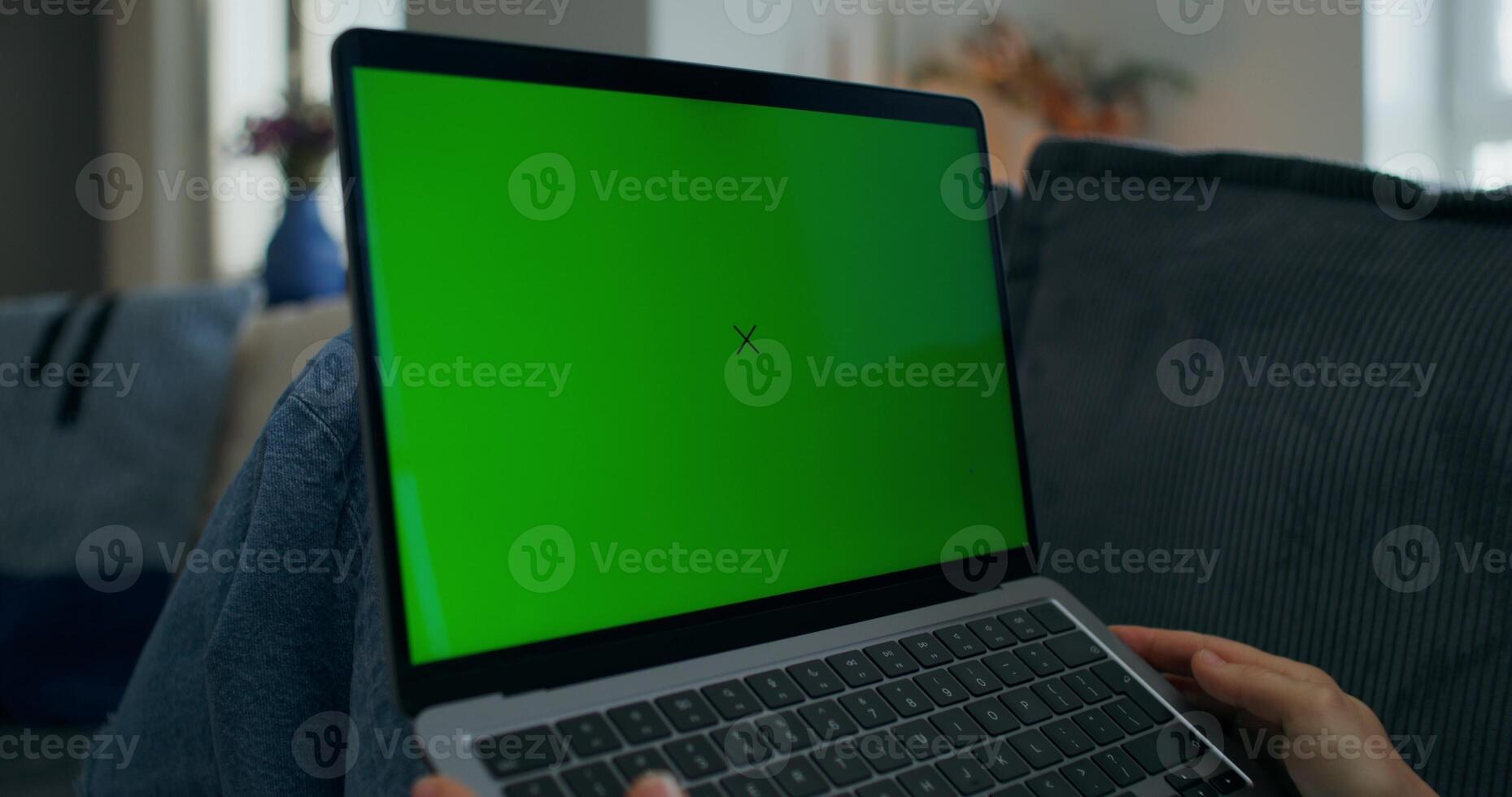 A person holding a laptop with a green screen photo