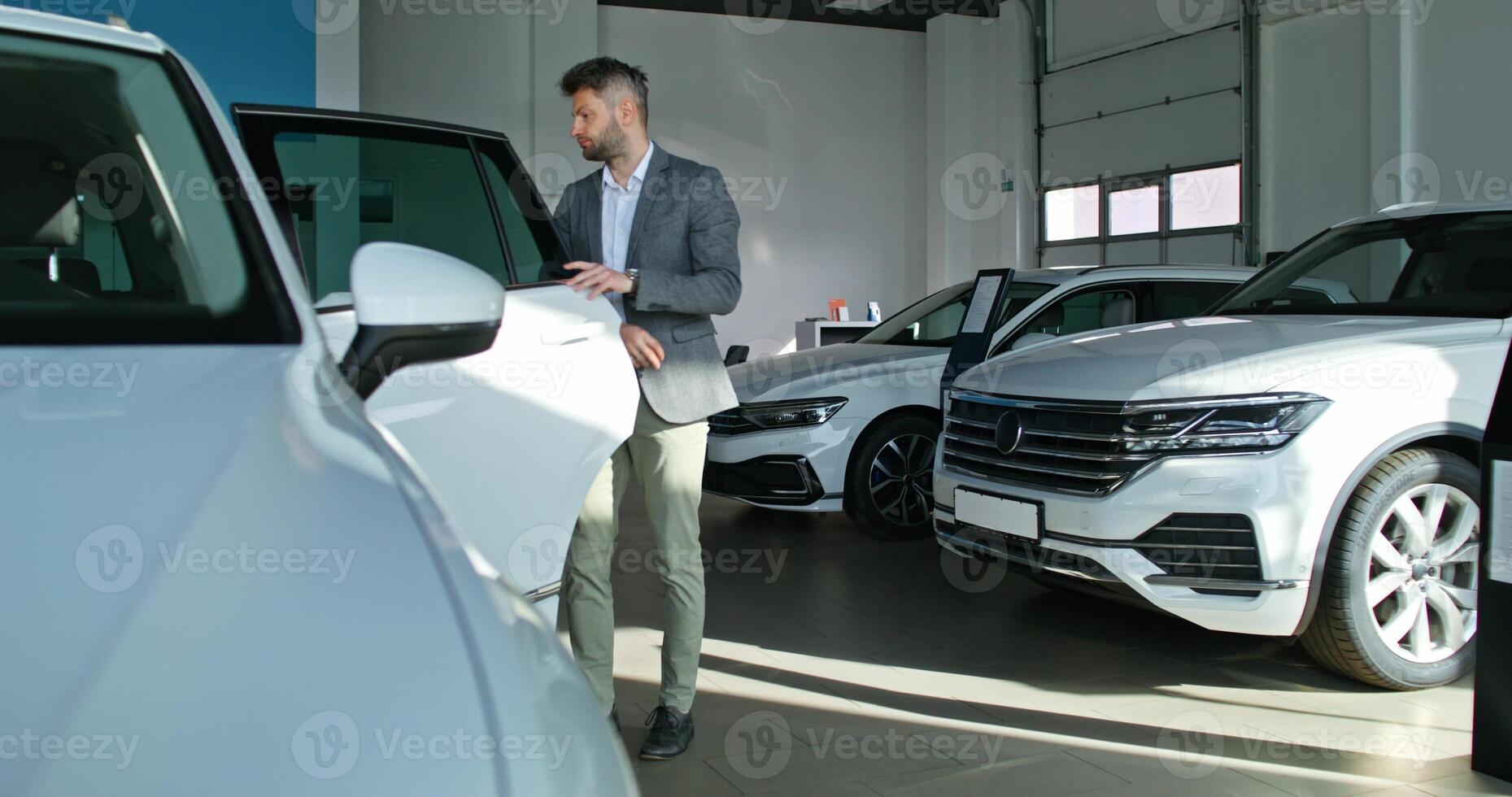 A man standing next to a white car in a car showroom photo