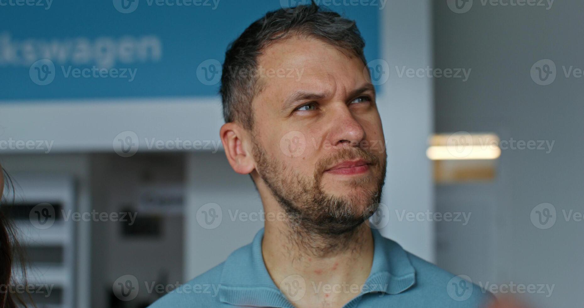A man in a blue shirt standing in front of a wall photo
