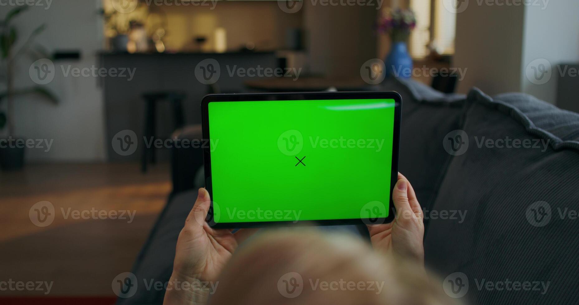 A woman holding a tablet with a green screen photo