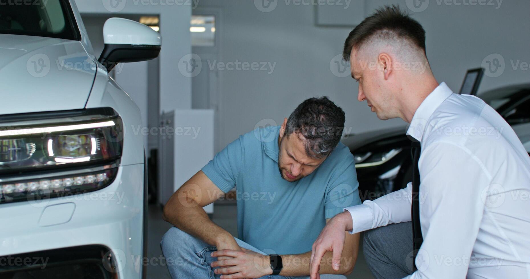 Two men looking at a car in a dealership photo