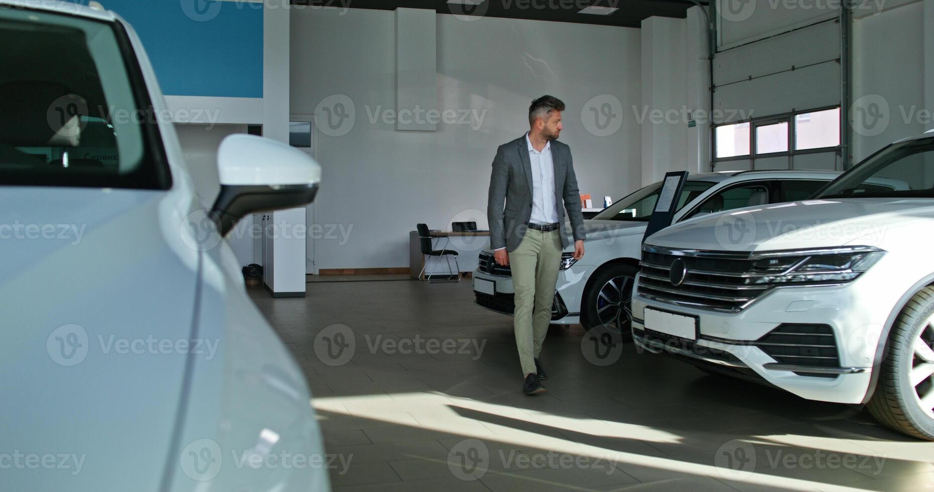 A man in a suit standing in front of a white car photo
