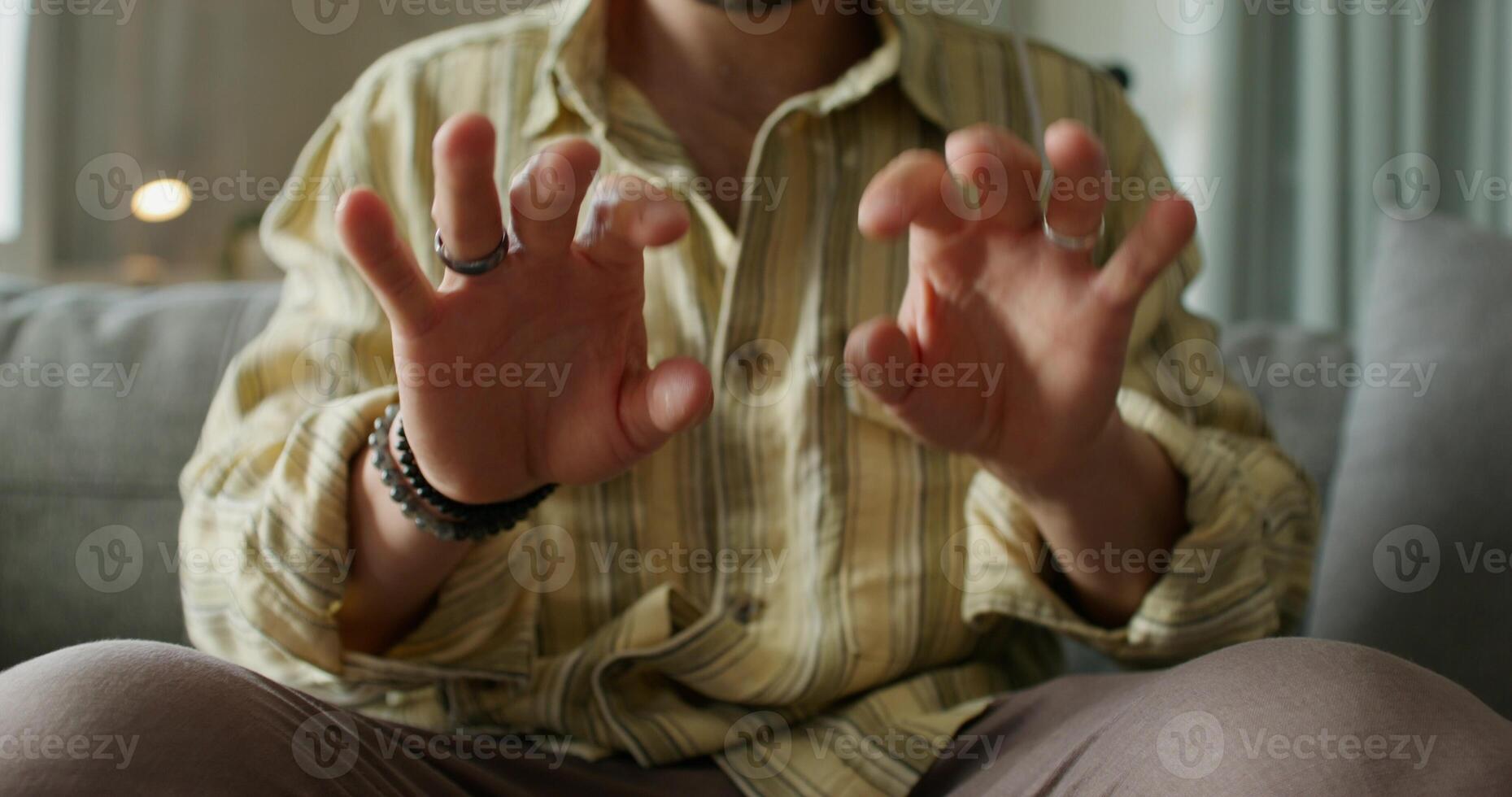 A man is sitting on a couch and making gestures photo
