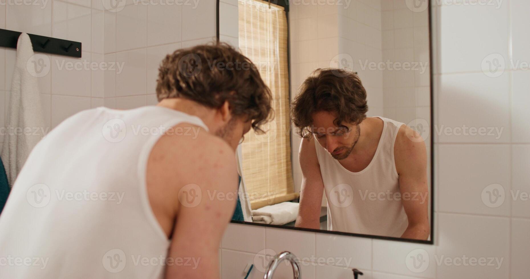 A man is looking in the mirror while brushing his teeth photo