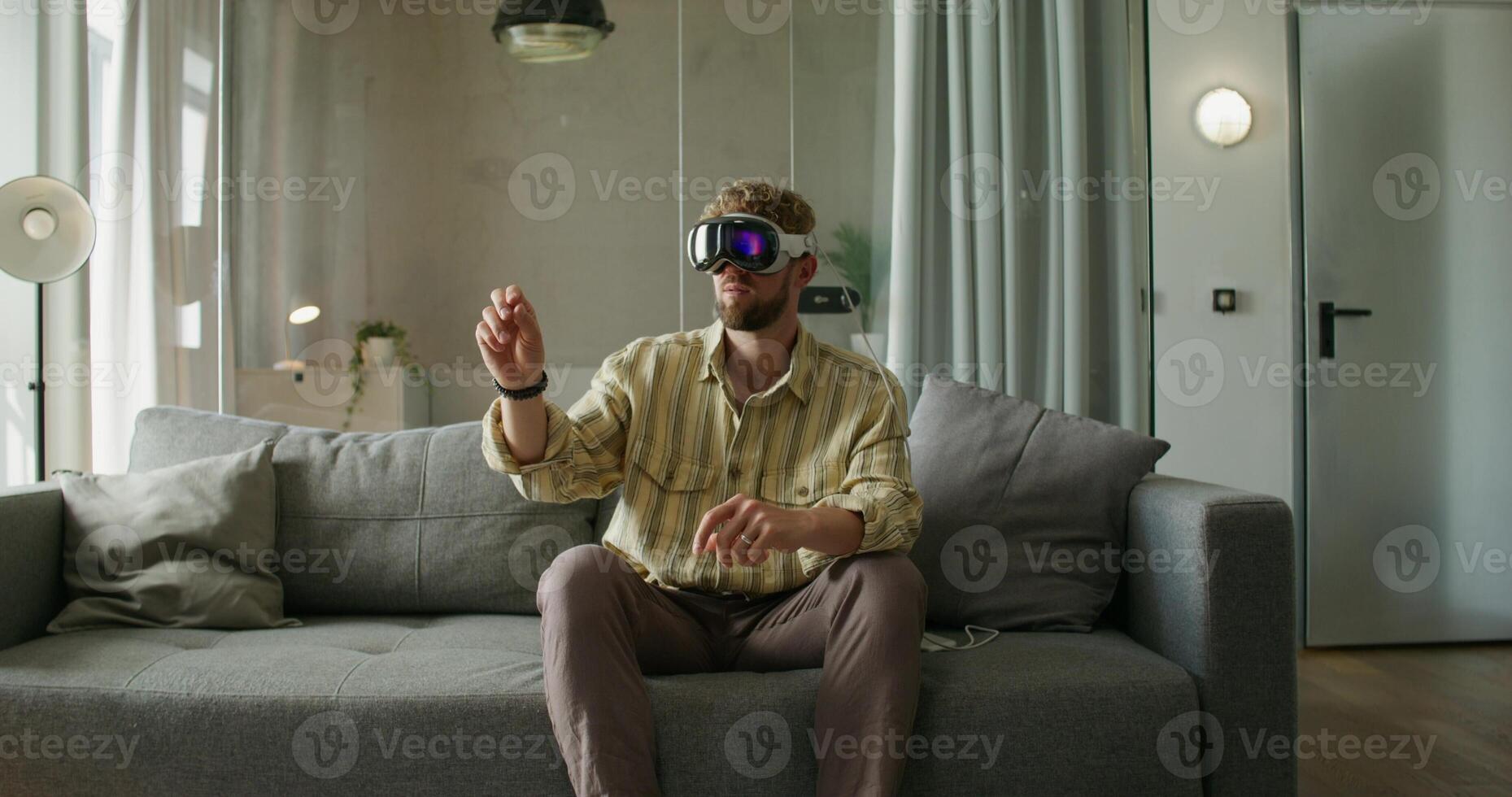 A man wearing virtual reality glasses sitting on a couch photo