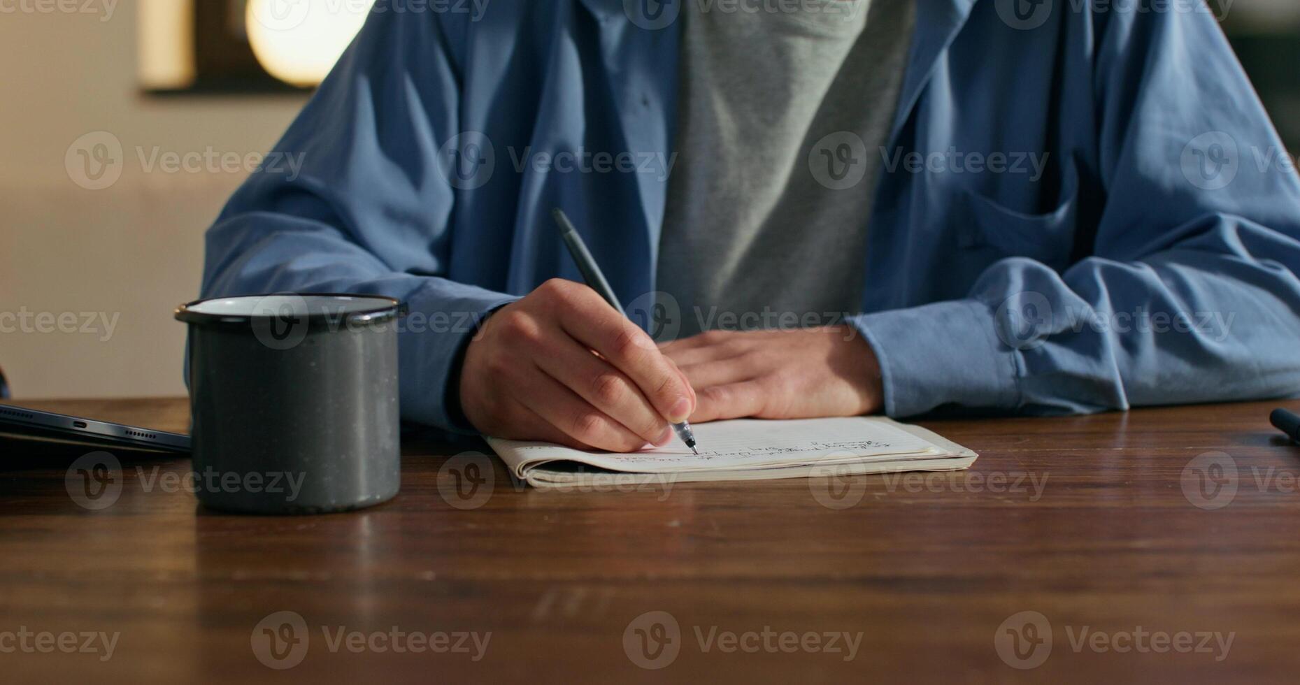 A person sitting at a table with a notebook and pen photo