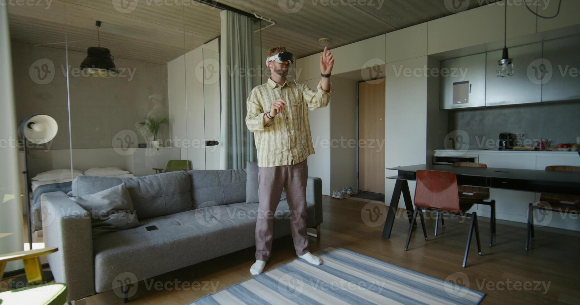 A man standing in a living room with a couch and a window photo