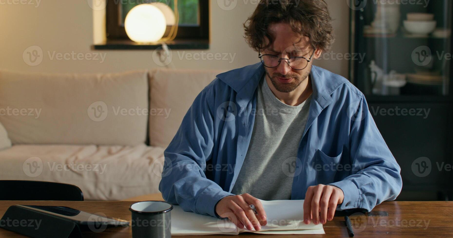 A man in glasses is sitting at a table with a laptop photo