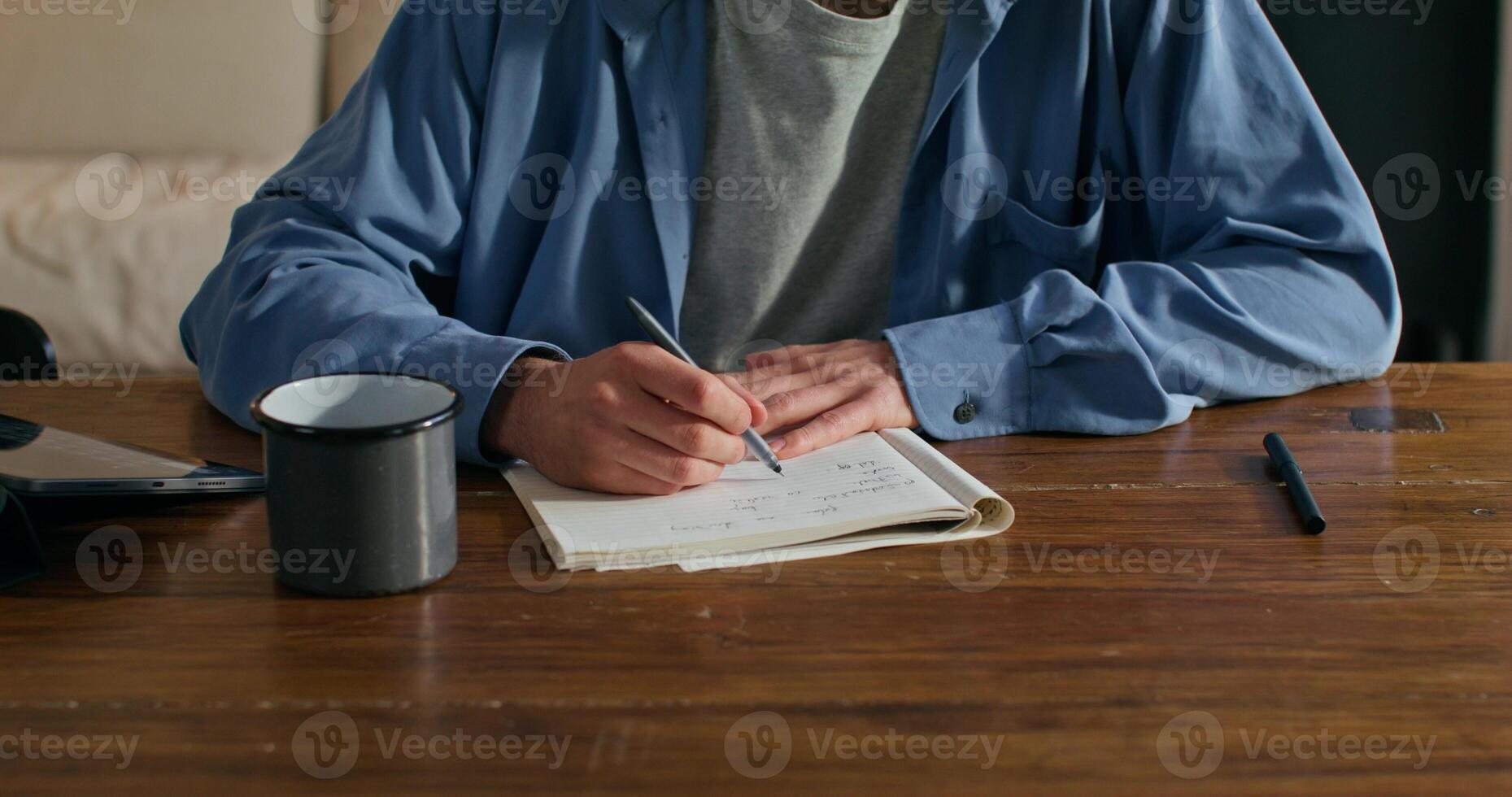 A man sitting at a table with a notebook and pen photo